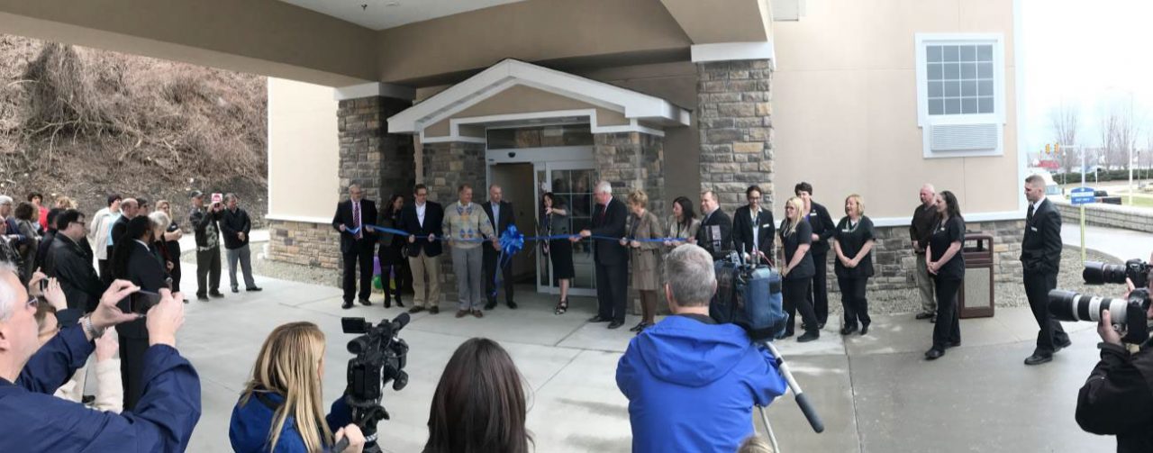 people cutting the ribbon at the coblestone hotel and suites 