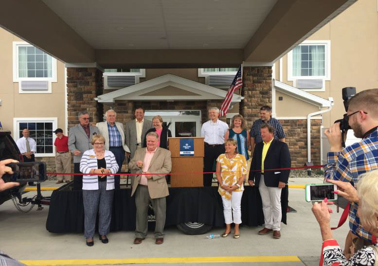 people cutting the ribbon at the cobblestone hotel and suites 