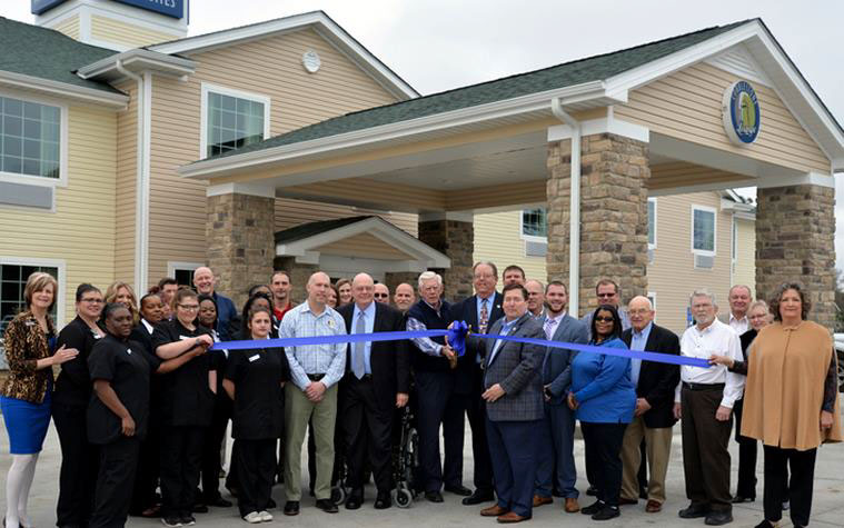 people cutting the ribbon at the new cobblestone inn and suites 