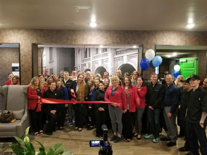 people cutting the ribbon at the new cobblestone hotel and suites 