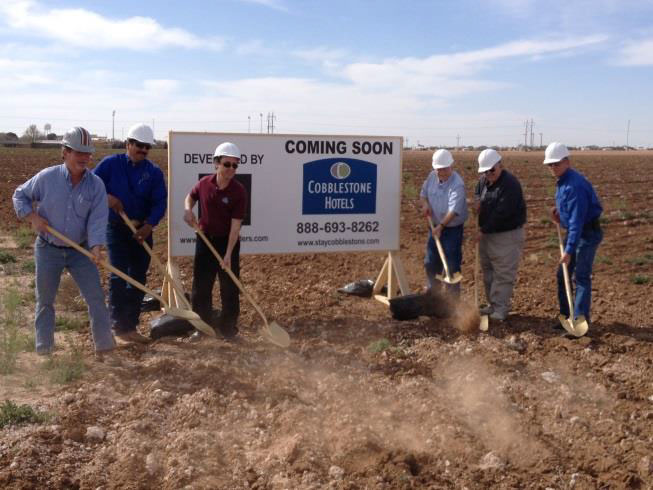 men with shovels breaking ground on the new cobblestone inn and suites 